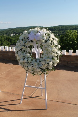 A white wreath near the Visitor Center with white luminary bags in the background.