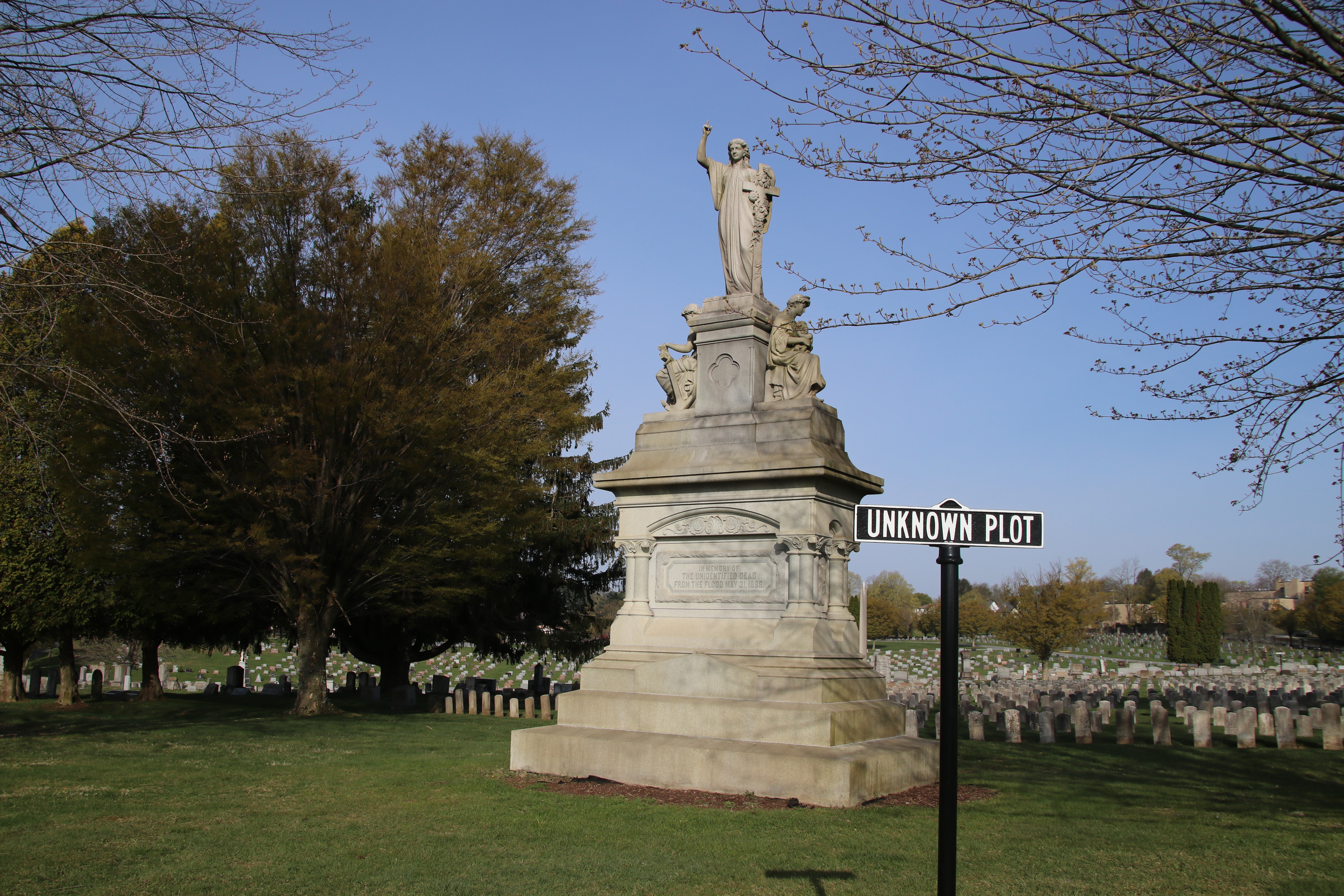 A statue with white headstones behind it