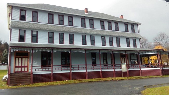 A large three-story building with lots of windows and a large porch.