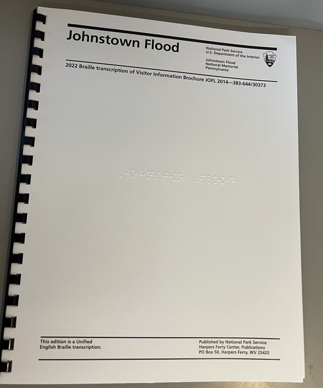 A white bound booklet with braille