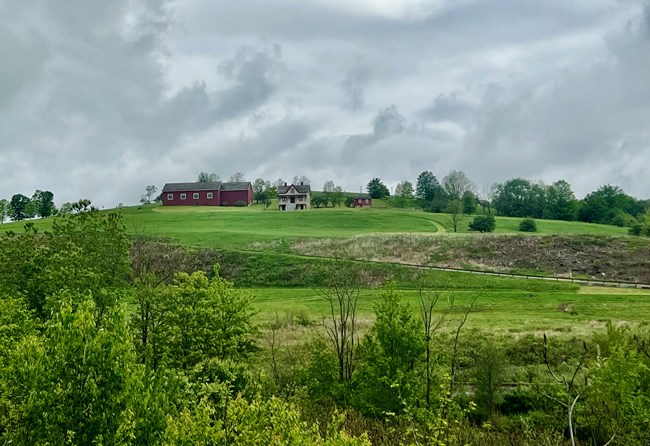 A barn structure and farmhouse on a hill