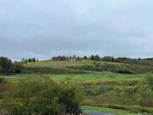 A view of the hillside with a red barn and farmhouse from the trail