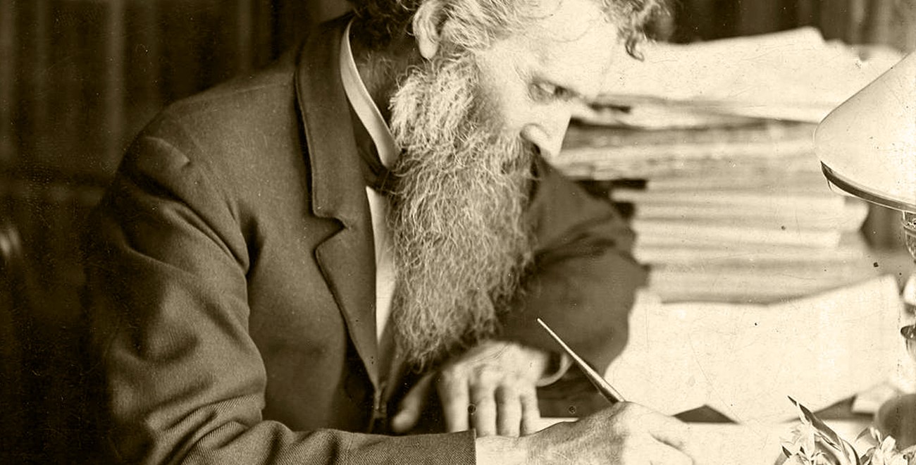 A mature John Muir, writing at his desk.