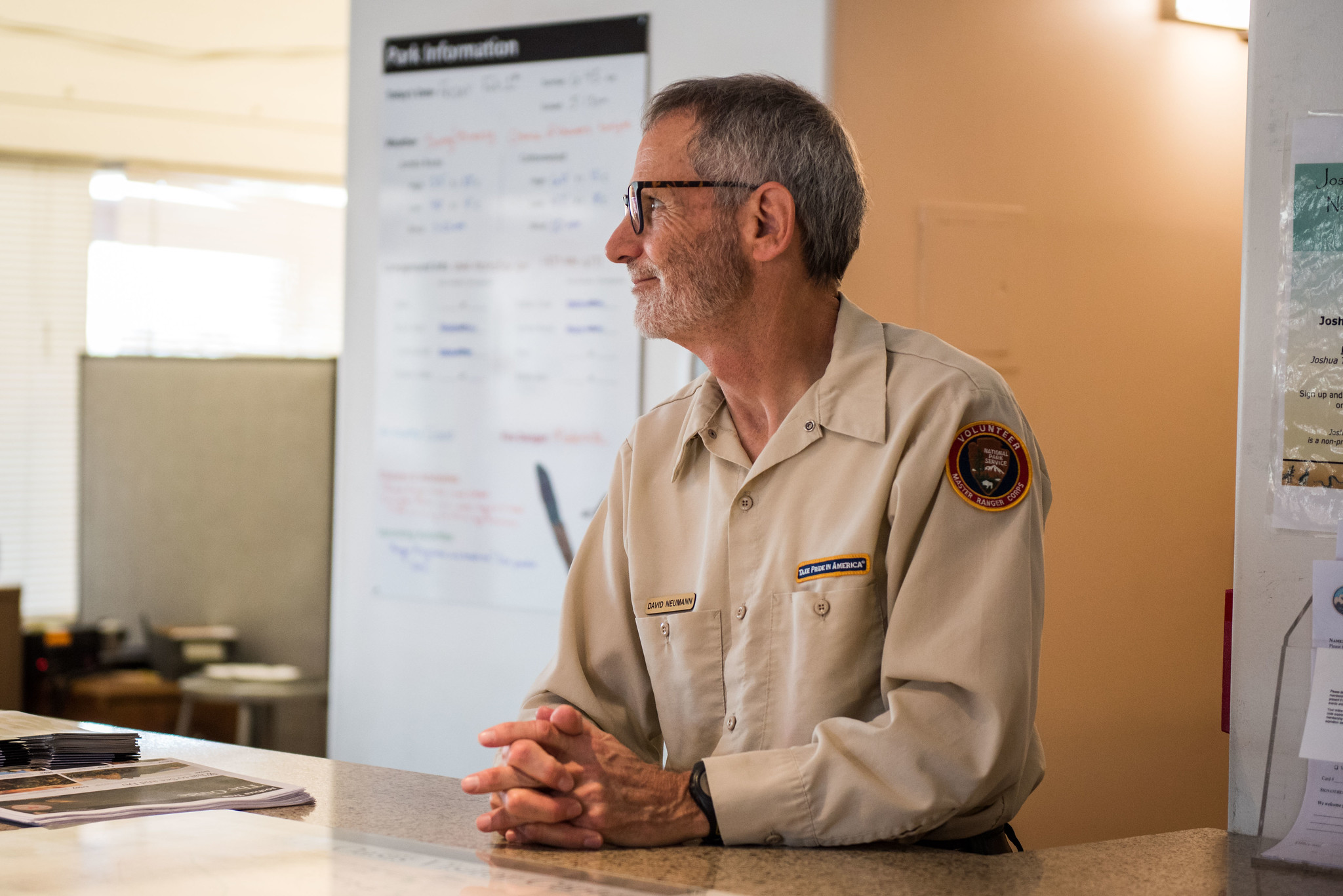A volunteer stands behind a visitor center front desk.