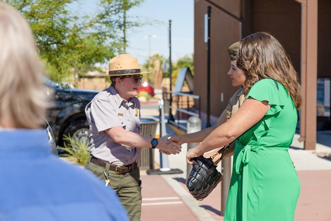 A ranger in NPS uniform shakes hands with two people, one who is in military uniform