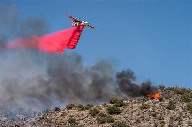 A plane spraying fire retardant over a desert landscape