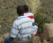 two students sit on a rock and look out over the desert