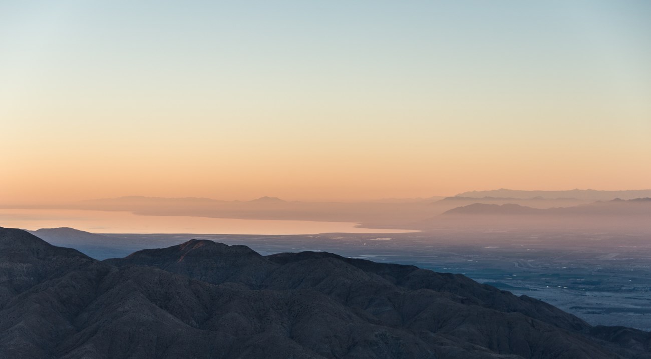 Looking out over the Salton Sea from Keys View. It is just after sunset and the light is very pink. The foreground mountains are blue.