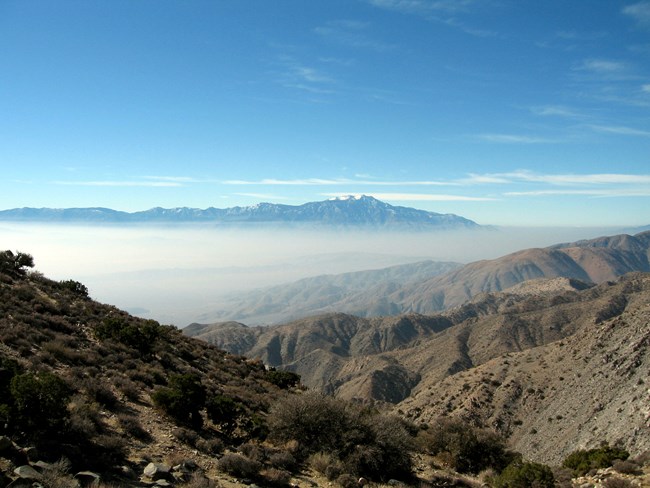A valley with blanketed in smog and surround by mountains.
