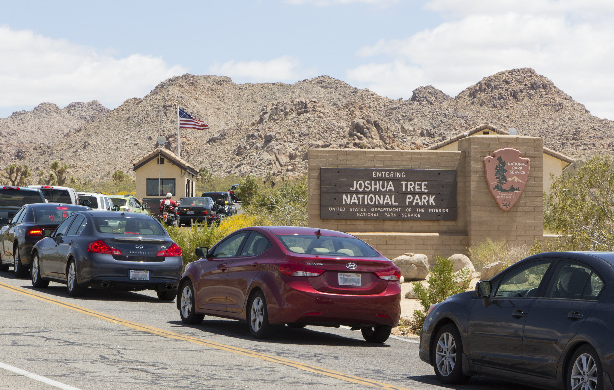 West Entrance Line a line of cars heading past a sign that says, Entering Joshua Tree National Park
