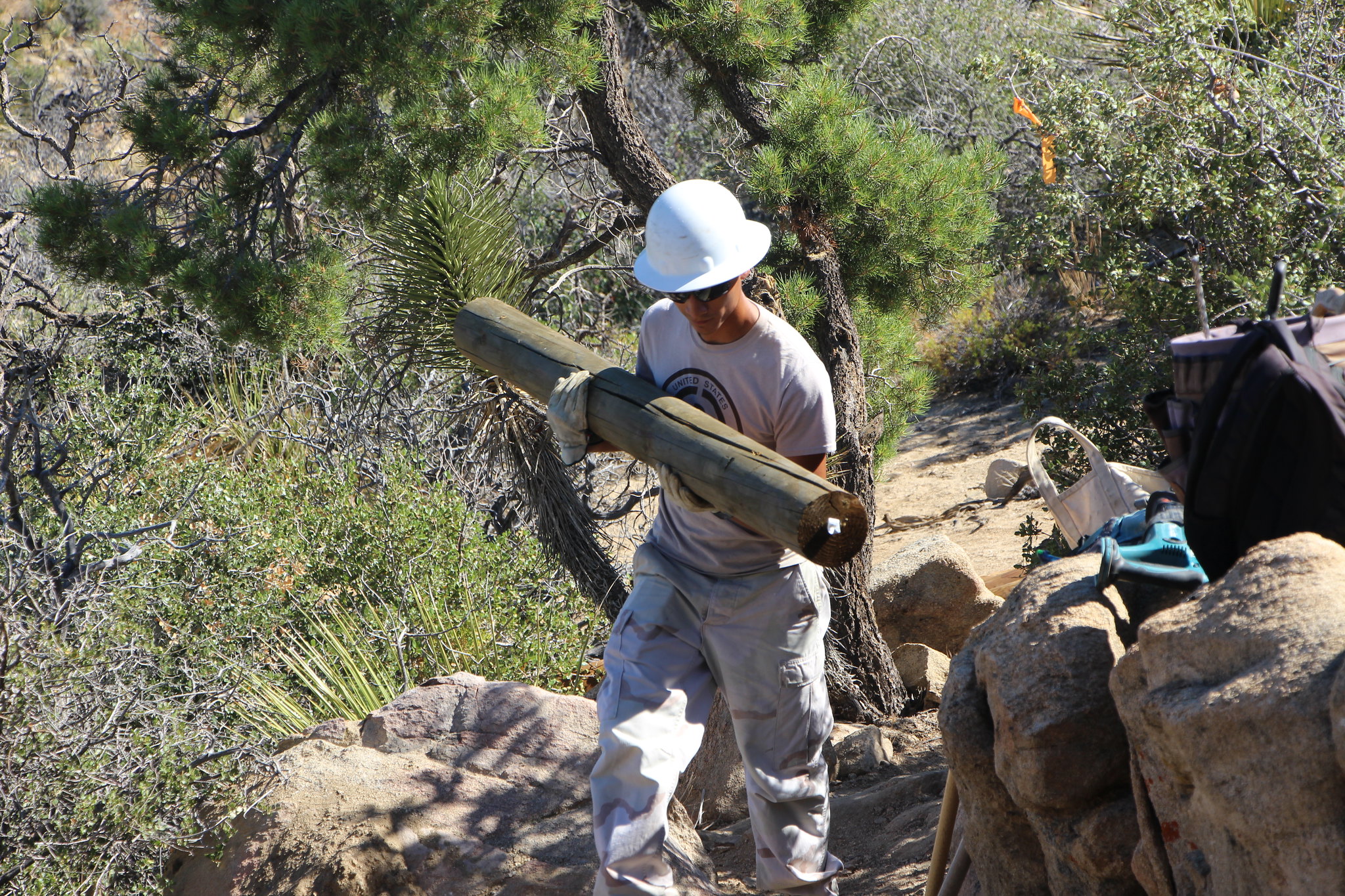 Youth Conservation Corps member holding a large log