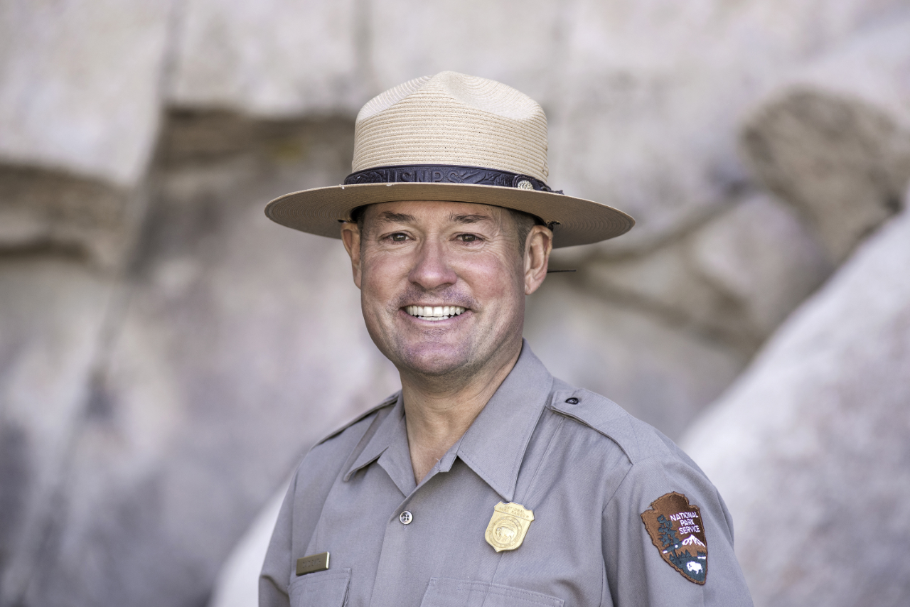 A ranger in uniform smiles at the camera