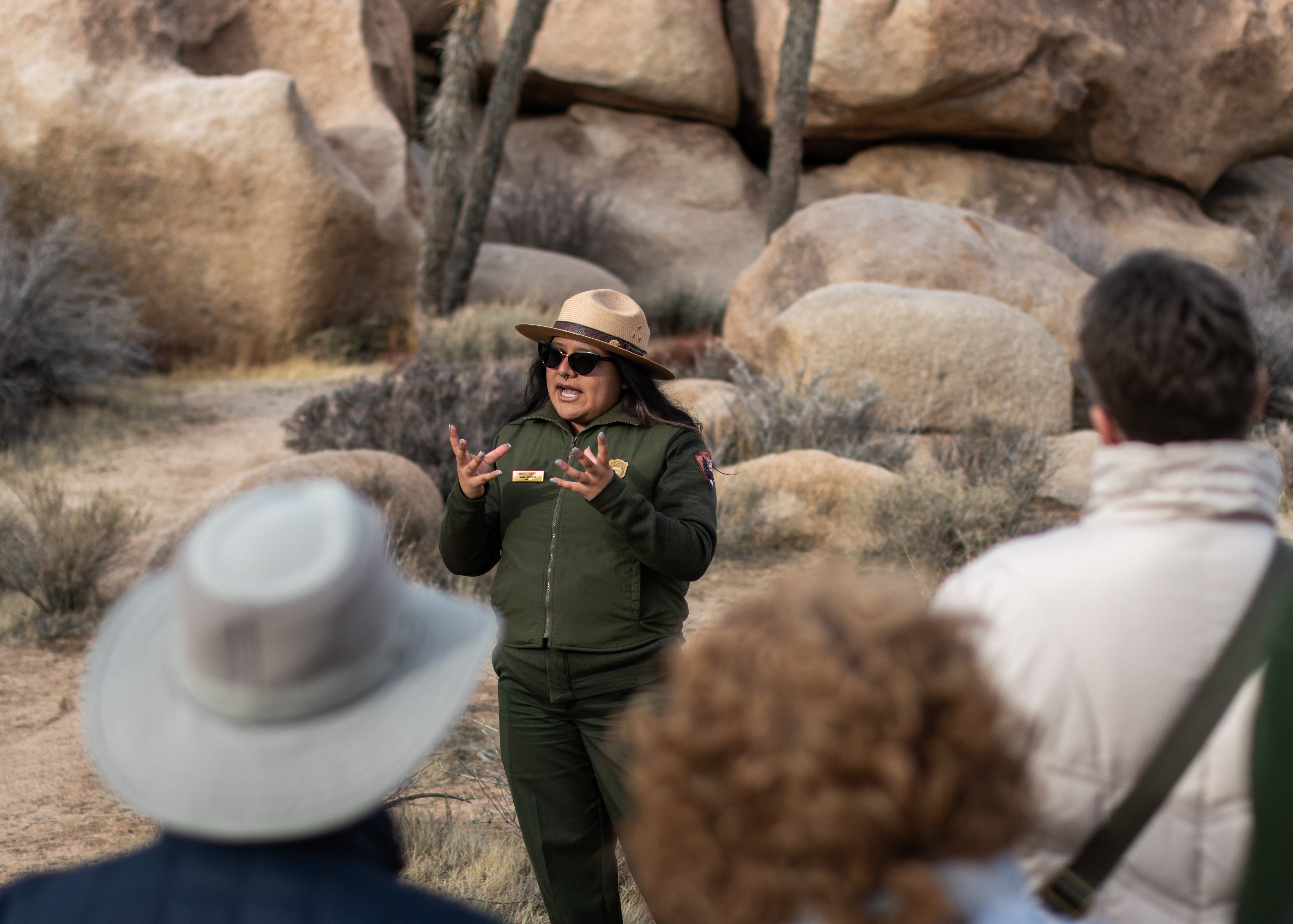 A Park Ranger giving tour with blurred park visitors in the foreground.