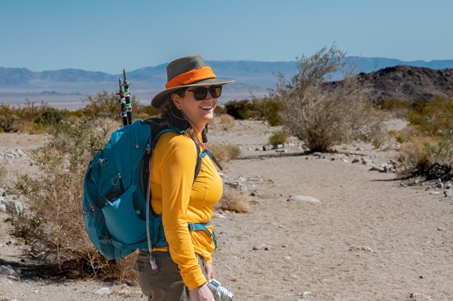 A women dressed in sun protective clothing with Joshua Tree Landscape