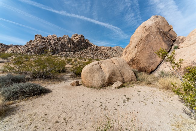 A backcountry campsite in a desert landscape with boulders, mountains, and desert vegetation
