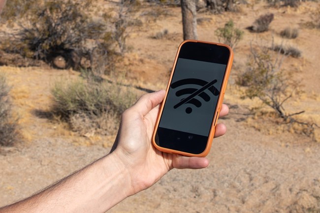 A hand holding a phone with a no connection symbol