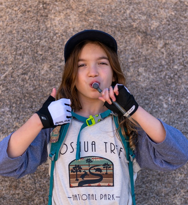 A child drinks water and give the thumbs up sign