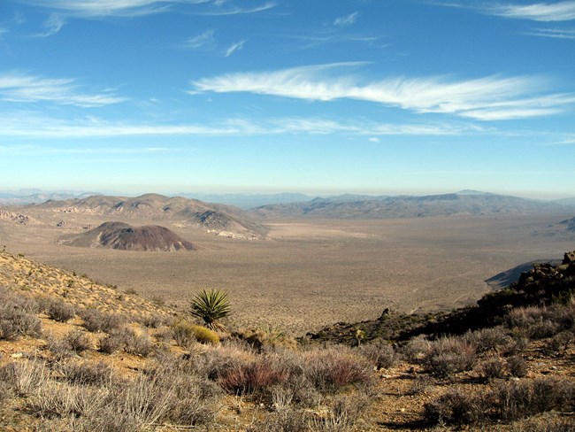 An expansive view over a desert valley with mountains in the background