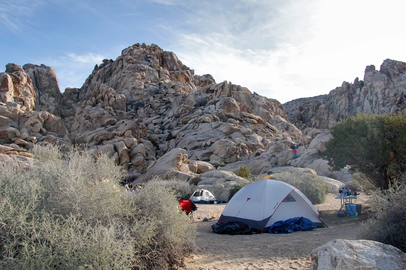 Sheep Pass group campground site Color photo of a group campsite at Sheep Pass campground. One dome tent is in the right foreground, with a smaller tent in the background against massive rock formations. People are seen climbing the rocks to the right background.