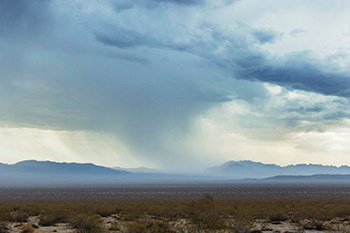 A rain cloud over distant mountains