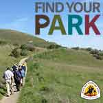 A group hiking along a trail through green, hilly landscape