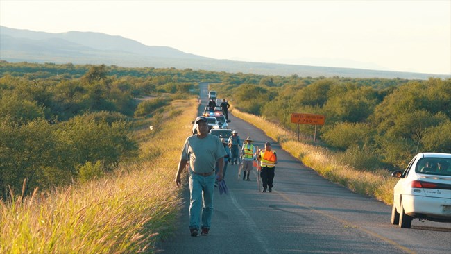 The Pilgrims in route Pilgrims travel along a road on their way to Magdalena in Sonora as a car passes by.