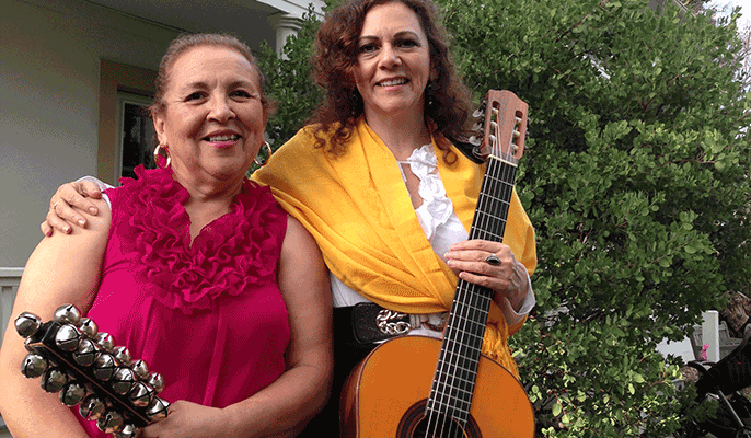 musicians smiling in front of historic adobe