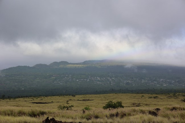 Rain clouds gathering at the peak of a green shield volcano