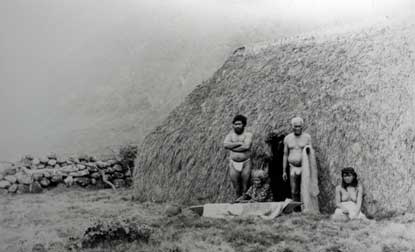 A group of Hawaiians at their pili grass hut in the volcano crater, Kalaupapa
