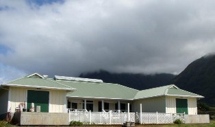 A one story light-colored building with a low white fence around the front.