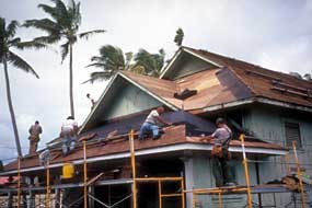 Five people on a roof with construction tools are working on the roof.