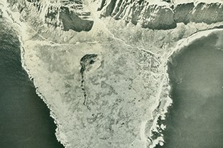 A black and white image of a peninsula with a crater in the middle