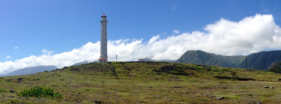 A very tall, white, and cylindrical structure on the left side with tall cliffs on the right side