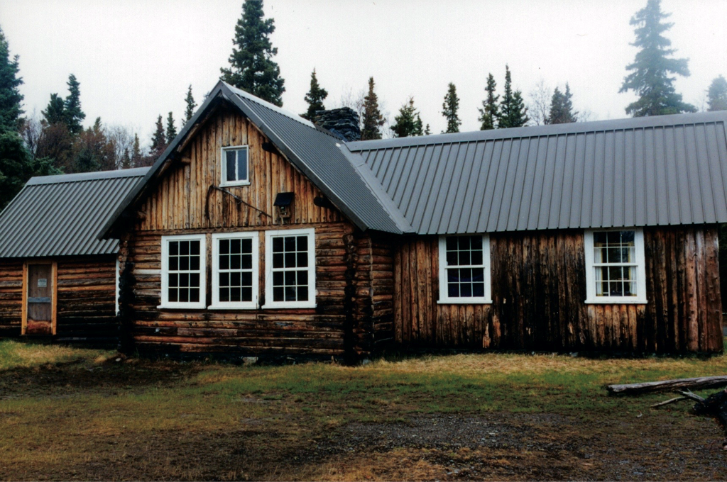 Former National Marine Research Station large log building with 2 windows on right wing, 3 windows on main structure and door on left wing.