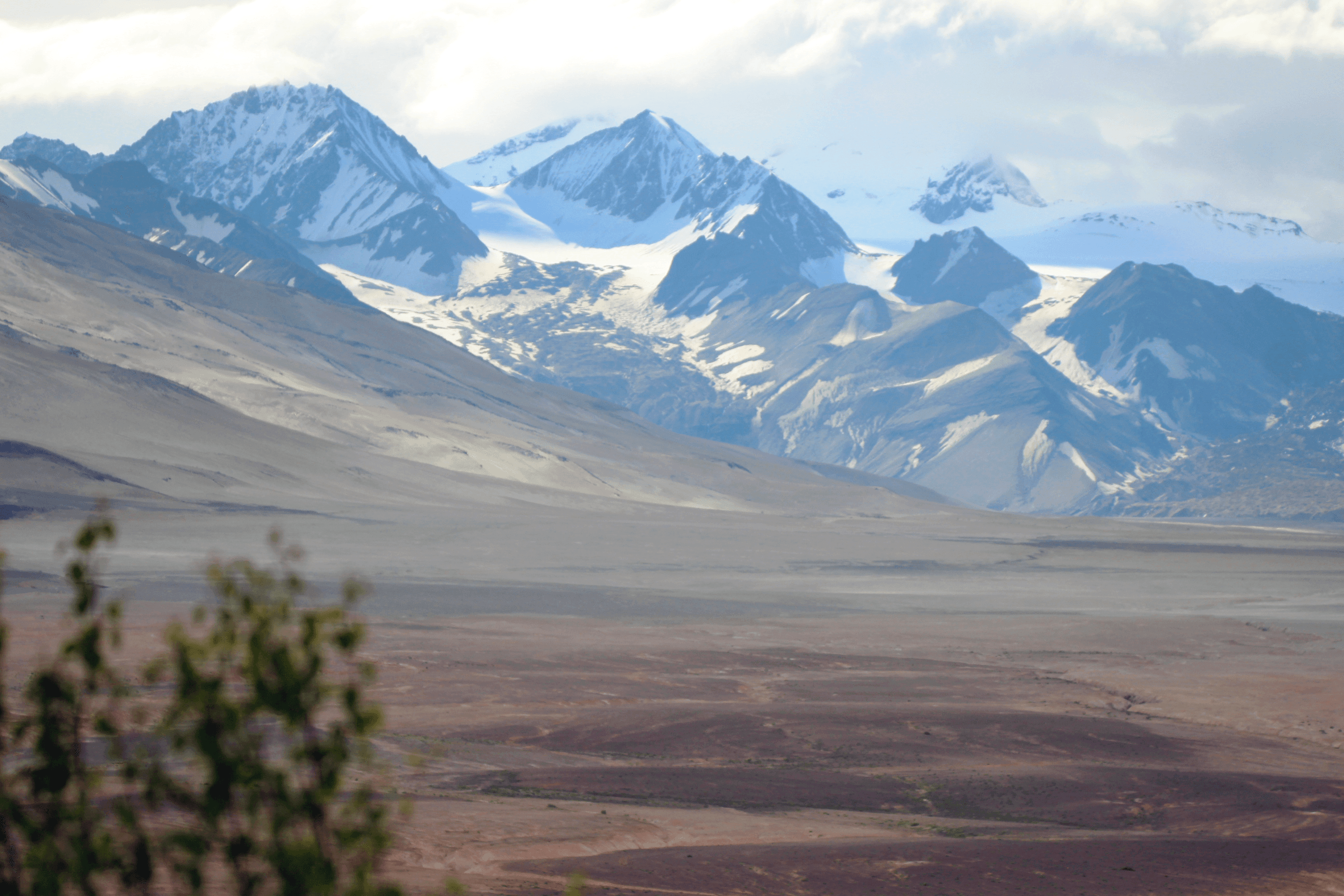  A barren, ashy valley surrounded by snow-capped mountains