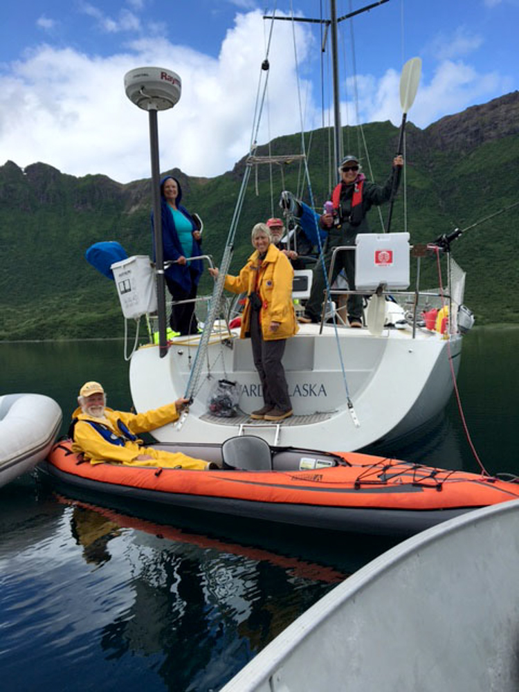 Visitors wave from a sail boat and kayak