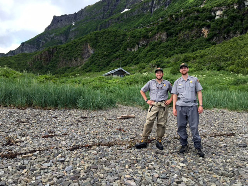 Two rangers stand in front of their cabin