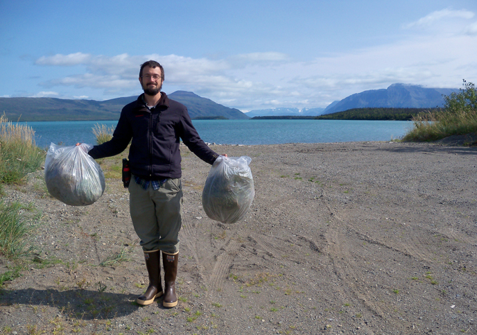 person standing with plastic bags filled with non-native plants