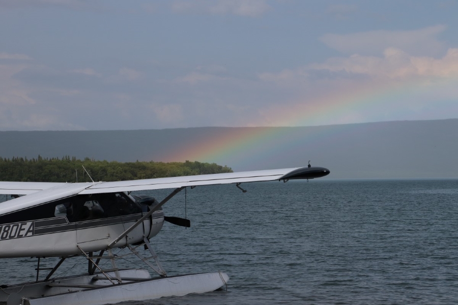 A float plane on the water with a rainbow in the background