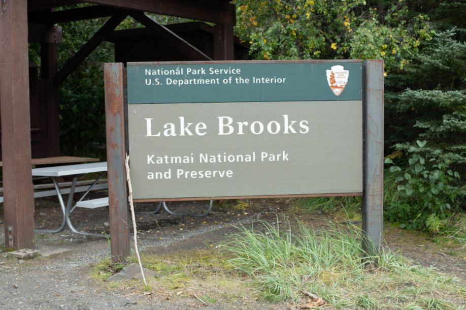 Park entrance sign that says National Park Service, US Department of the Interior with arrowhead followed by Lake Brooks, Katmai National Park and Preserve