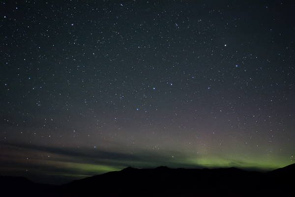 Green and pink lights from the Aurora over mountain ridge