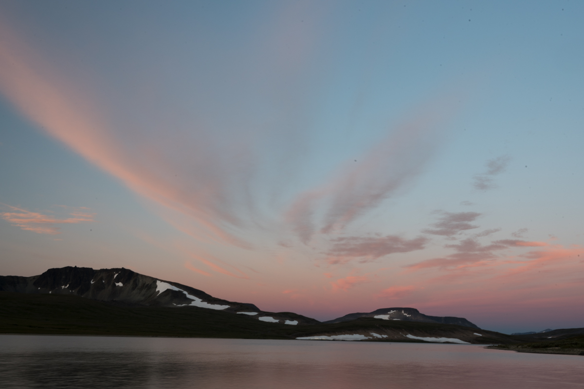 Evening Light, Mirror Lake A lake with snow patches on the mountains and pink clouds in the sky