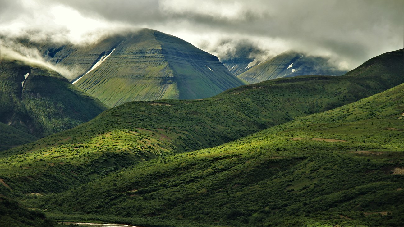 Lush green hillsides with mountains in the background