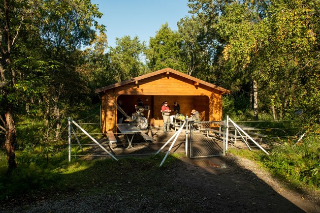 Several people inside a picnic area surrounded by an electric fence