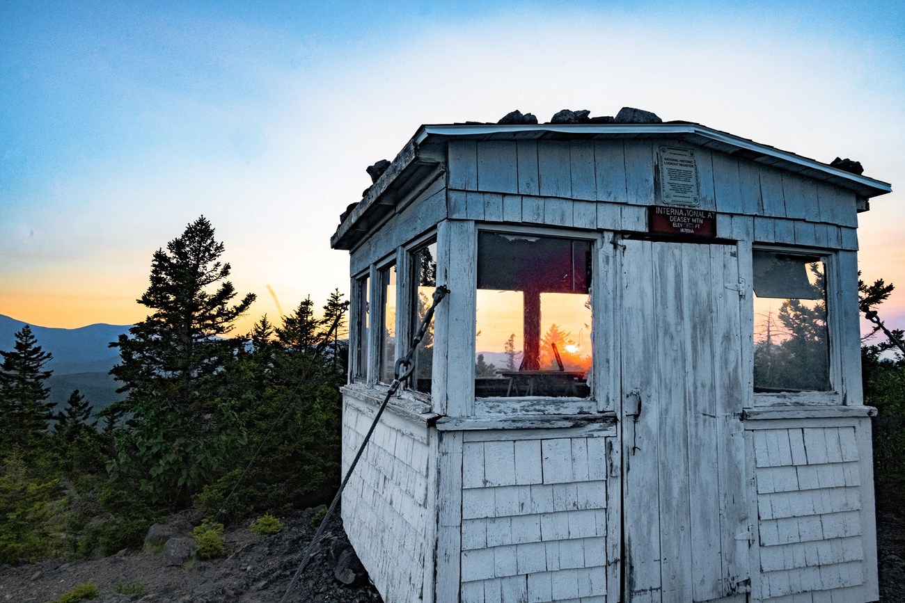 a white wooden building ontop of a mountain at sunset