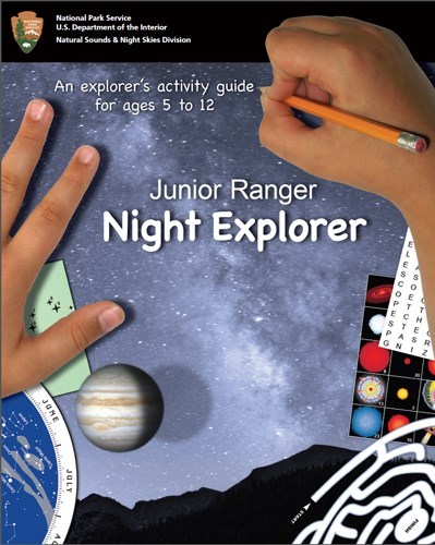 Front cover of the Junior Ranger Night Explorer book showing a child's hands holding a pencil and an image of the night sky.