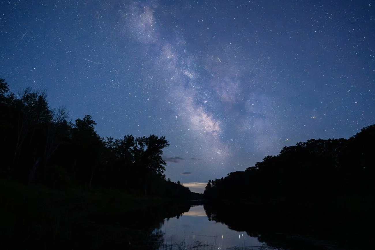 Milky way Lunksoos Picnic Area The Milky Way illuminated clearly over the East Branch Penobscot River. Silhouettes of the woods and landscape line both sides of the river. The Milky Way and the bright stars reflect onto the serene river.
