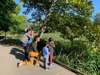 A family, kneeling on the boardwalk, doing a junior ranger book.