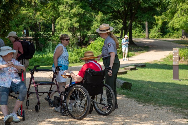 A park ranger speaks with visitors using a wheelchair and walkers.