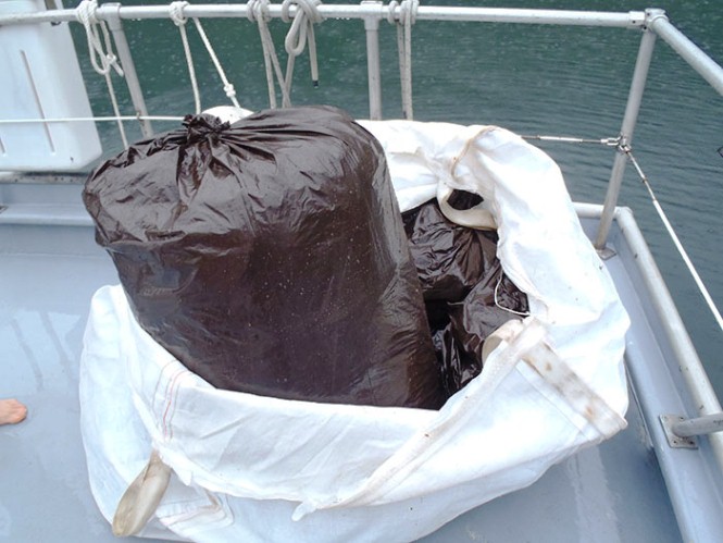 Trash bags of marine debris are piled on the back deck of a boat.